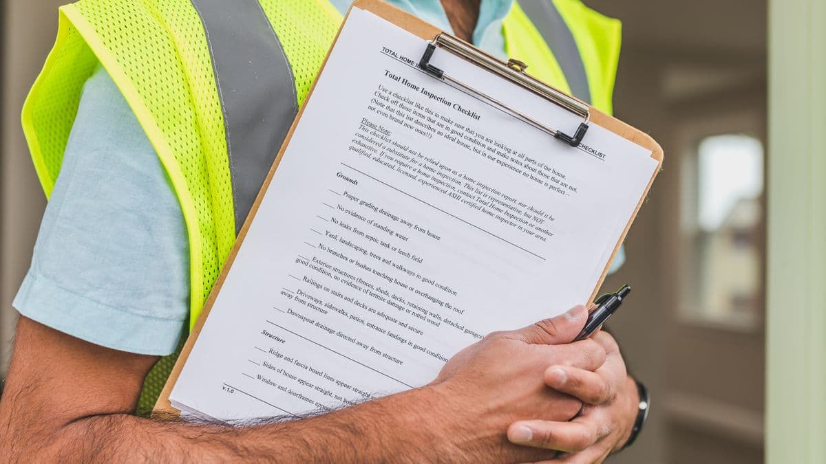 A construction worker in a high-visibility vest holding a clipboard with a printed inspection checklist